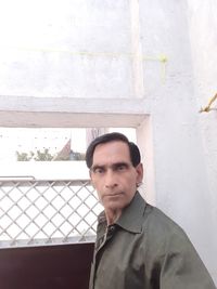 Portrait of young man standing against wall