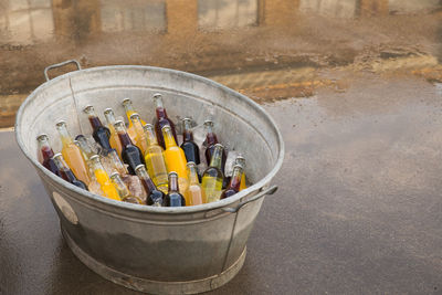 High angle view of bottles with ice cubes in container on footpath