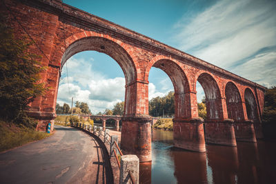 Arch bridge over river against sky