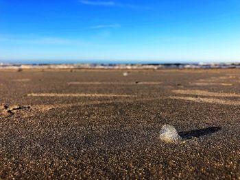 Surface level of sandy beach against blue sky