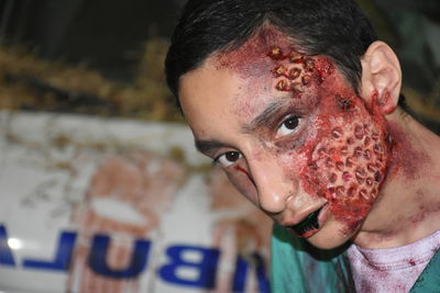 Close-up portrait of teenager boy with zombie face during halloween