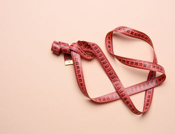 Twisted white measuring tape on a beige background, copy space. weight loss conce