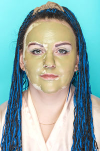 Portrait of young woman against blue background