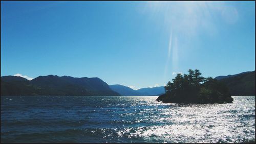 Scenic view of sea and mountains against clear blue sky