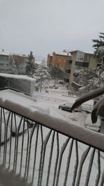 Hand on snow covered railing against sky