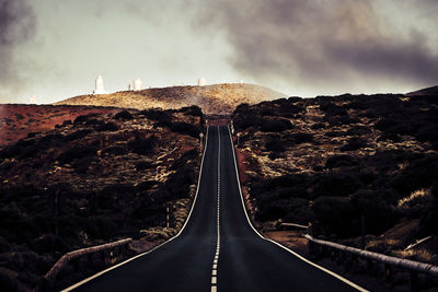 Road leading towards mountain against sky