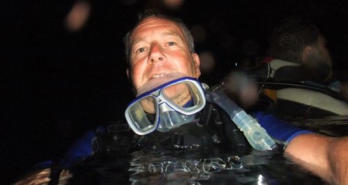Close-up of man with arms raised against black background
