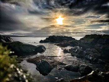 Scenic view of rocks in sea against sky during sunset