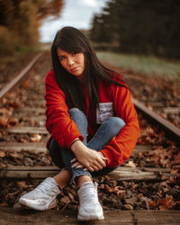 Portrait of young woman sitting on railroad track