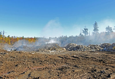 Smoke emitting from volcanic landscape against sky