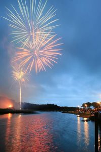 Firework display over sea against sky at night