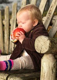 Full length of boy sitting on wood