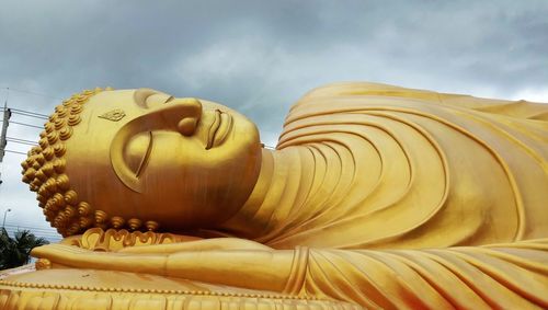 Low angle view of buddha statue against sky