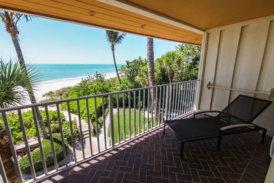 Walkway by sea against sky seen through balcony