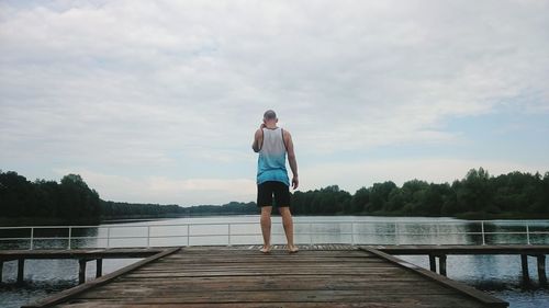 Rear view of man on pier on lake