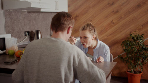 Couple sitting at kitchen while eating meal