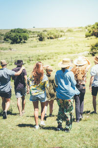 Rear view of people walking on field