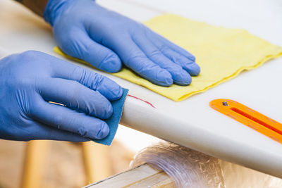 Surfer with protective gloves sanding a repair on the surfboard.