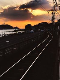 Railroad tracks against sky during sunset