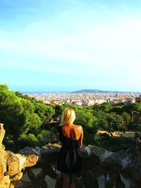 Rear view of woman standing against sky on sunny day