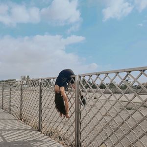 Full length of boy on fence against sky