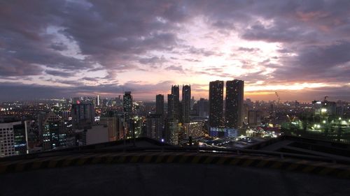 Illuminated cityscape against sky during sunset