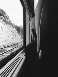 Rear view of man sitting on seat looking through train window