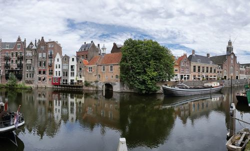 Reflection of buildings and trees in river against sky