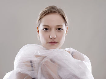 Portrait of young woman in plastic against gray background