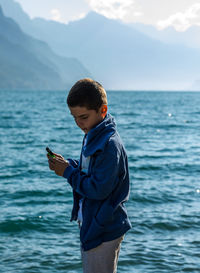 Boy using mobile phone in sea