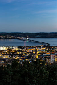 High angle view of illuminated city by sea against sky