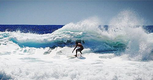 Man surfing in sea against sky