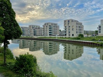 Reflection of buildings and trees in lake against sky