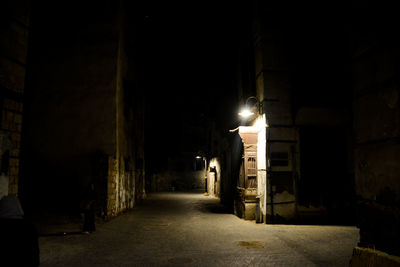 Empty alley amidst buildings in city at night