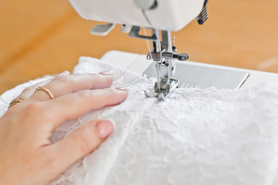 Close-up of cropped hands sewing wedding dress