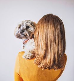 Woman carrying dog while standing against wall