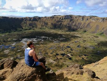 High angle view of hiker looking at view while sitting at crater lake of rano kau