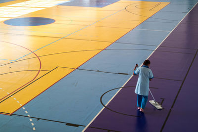 Rear view of woman cleaning basketball court