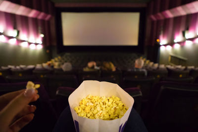 Cropped hand having popcorns in theater