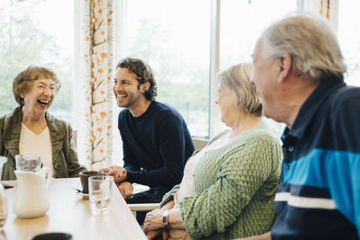 Smiling man visiting his grandmother and her friends at retirement home