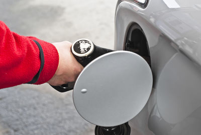 Cropped hand of person fueling car at gas station