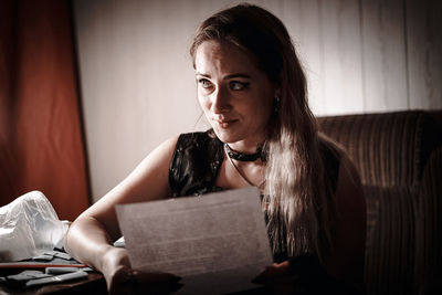Young woman sitting on book at home