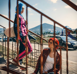 Low angle view of young woman sitting on railing