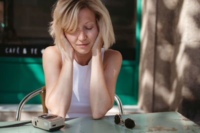 Woman looking at camera while sitting on table at home