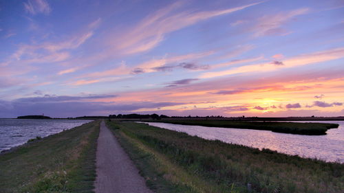 Footpath on fehmarn amidst baltic sea against sky during sunset