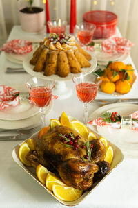 A festive table with baked chicken, tangerines, candles, cake and glasses of wine. holiday.