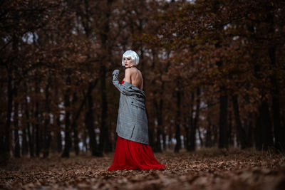 Woman with umbrella standing on field in forest