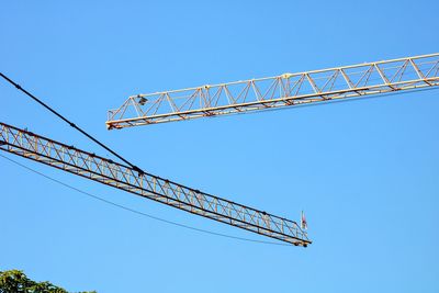 Low angle view of crane against clear blue sky