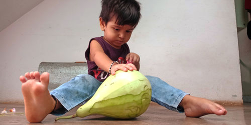 Full length of boy holding food while sitting on floor