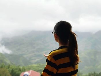 Rear view of woman looking at mountains against sky